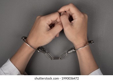 hands of a doctor in handcuffs close up,arrest of a surgeon.
				