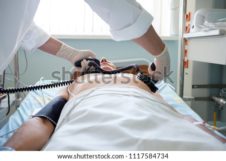 hands of doctor holding defibrillator electrods, performing defibrillation or electropulse therapy