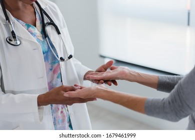 Hands of a doctor holding hands of elderly patient. Checking symptoms of stroke. Medical care and support concept.