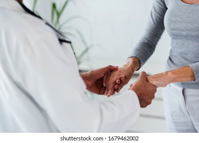 Hands Of A Doctor Holding Hands Of Elderly Patient. Checking Symptoms Of Stroke. Medical Care And Support Concept.