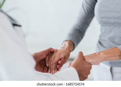 Hands Of A Doctor Holding Hands Of Elderly Patient. Checking Symptoms Of Stroke. Medical Care And Support Concept.