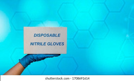 The Hands Of A Doctor In Medical Gloves Holding A Cardboard Box  Which Contains Disposable Nitrile Gloves. Prevention Of Coronavirus Covid-19