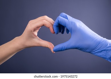 Hands Of A Doctor In Medical Gloves In The Shape Of A Heart On A Blue Background. Patient And Doctor's Hand. Banner For Website With Copy Space.