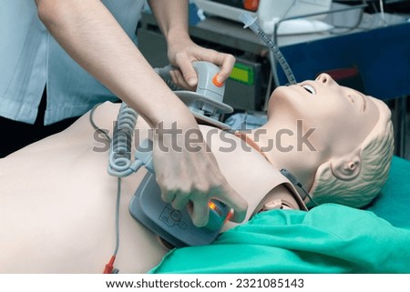Hands of doctor physician performning cardioversion with defibrillator on a mannequin,advance cardiac life support course training.Healthcare Concept