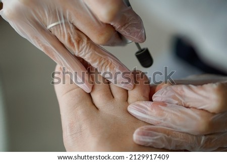 hands doing a pedicure on a man's leg with an apparatus