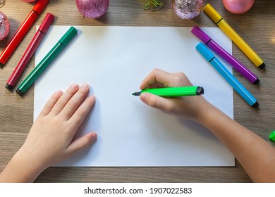hands draws Christmas tree and colored felt  tip pen  sitting at the table in the classroom 