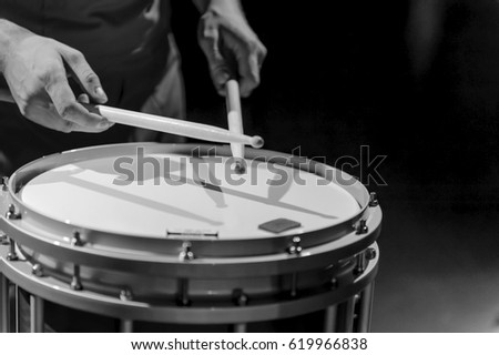 The hands of a drummer with a marching drum. Black and white photo of the hands of a musician