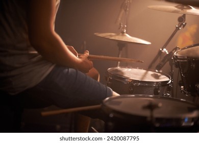 Hands, drummer and musician in performance at rock concert, music festival on stage and band. Closeup, artist and playing on drumstick for entertainment, sound or rehearsal on percussion instrument - Powered by Shutterstock