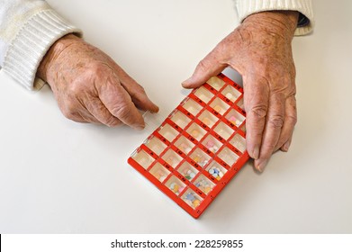 Hands Of An Eighty Eight Year Old Man Open A Pill Organizer Box. The Box Is Filled With A Variety Of Pills, And Is Divided Into Four Times A Day, Seven Days A Week