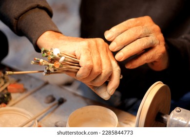 Hands of elderly craftsman man working in a workshop polishing opal stones and minerals to form precious jewelry - Powered by Shutterstock