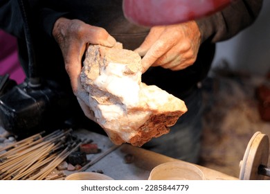 Hands of elderly craftsman man working in a workshop polishing opal stones and minerals to form precious jewelry - Powered by Shutterstock