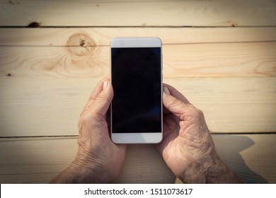 Hands of an elderly man holding and using a phone. The concept of teaching new technologies to older people, communication with the older generation. Image.
