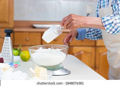 Hands Of An Elderly Man Using A Scales On A Table To Weigh Flour In A Kitchen