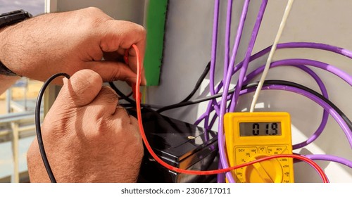 hands of an electrical technician checking with a polymeter the voltage and the correct installation of the equipment with selective focus.
