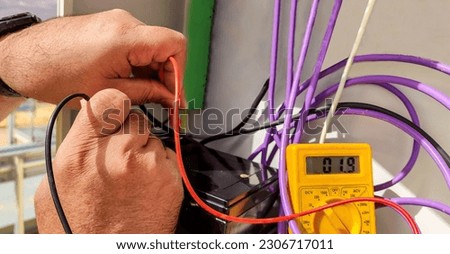 hands of an electrical technician checking with a polymeter the voltage and the correct installation of the equipment with selective focus.