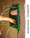 Hands electrical wiring is pulled through the hole in the wall of the drywall.