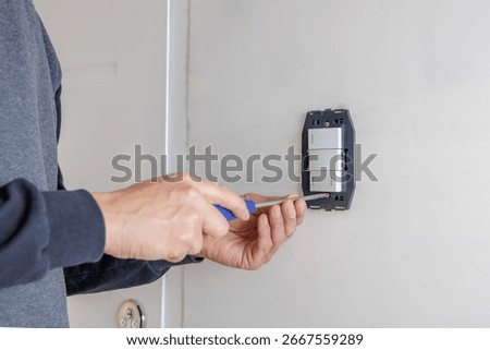 Hands of an electrician installing an electrical switch.
