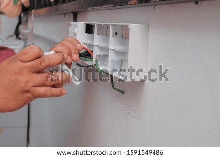 The hands of an electrician installing a power socket.