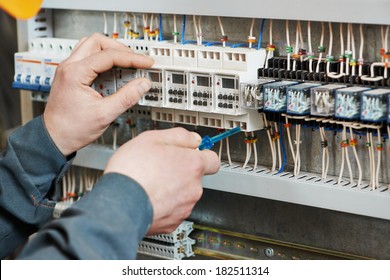 Hands electrician and screwdriver tighten up switching electric actuator equipment in fuse box