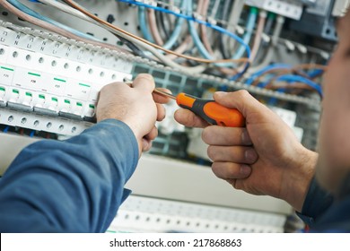 Hands of electrician with screwdriver tighten up switching electric actuator equipment in fuse box