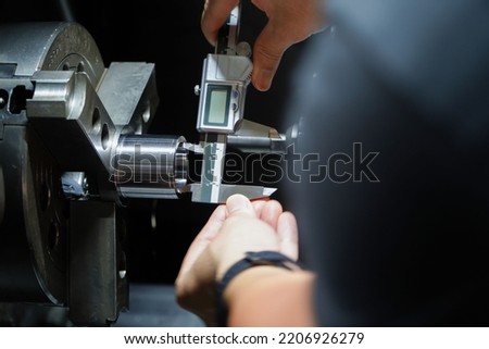 Hands of an engineer measures a metal part with a digital vernier caliper. Quality control of part machined on a lathe,Quality control concept of Qc.