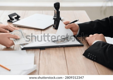 Hands exchanging money and documents on a wooden desk bribery corruption and illegal financial transactions, the interaction suggests a clandestine deal or unethical business practice