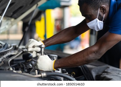 Hands Expertise car mechanic in auto repair service. Car maintenance and auto service garage concept. Black man wearing medical face mask protec virus corona