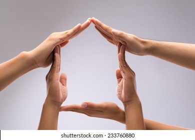 Hands of family members forming house shape