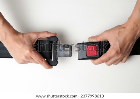 Hands fastened seat belt on white  background with copy space. Female hands with safety belt, close-up