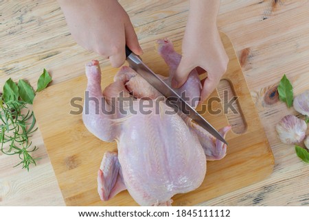 The hands of a female chef carves a whole chicken carcass on a wooden Board, the view from above. Top view