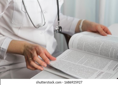 Hands of a female doctor holding a  medical journal in diagnostic cabinet. Doctor is waiting for patient. Stethoscope. Coronavirus.