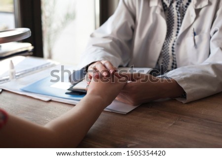 Hands of female doctor reassuring her patient selective focus background.