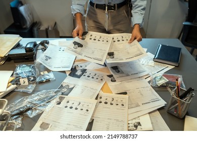 Hands Of Female Investigator Holding Criminal Profiles Over Desk With Documents While Learning Personal Information About Suspects