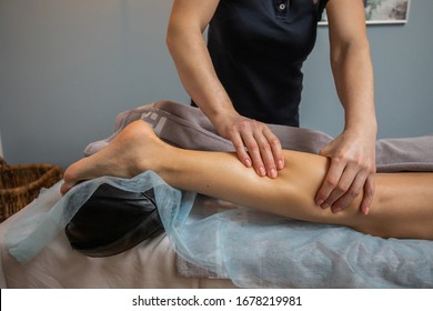 Hands of Female Masseur Master Makes Relaxing Leg Massage For Young Woman Close Up. The Masseur Kneads The Calf Muscle Of The Client - Powered by Shutterstock