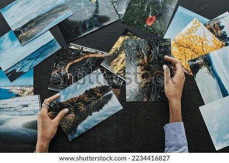 Hands of female photographer checking photos of landcapes she printed