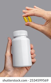 Hands female showing medical plastic bottle mockup as soft-gel capsules pour out. Medicine advertising mockup. Showcasing vitamins, dietary supplements, and nutrition products. Intake of omega-3
