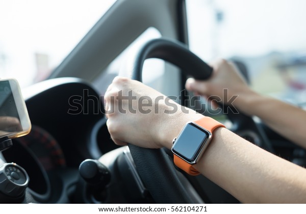 Hands of female\
with smart watch driving\
car.