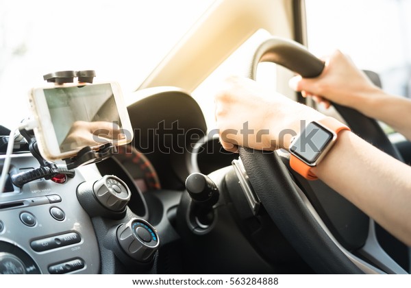 Hands of female with smart watch using GPS and\
driving car.
