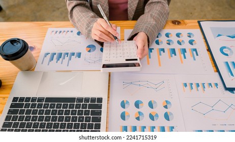 Hands of financial manager analyzing reports on desk, business plan and analyzing many chart graphs with laptop, calculator, pen, top view.