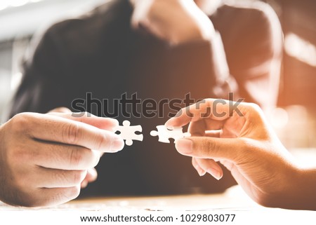 
Hands fingers businessman team work holding and join pieces two jigsaw connecting couple puzzle piece for matching to goals target, success and start up new project in office.  Business Concept.