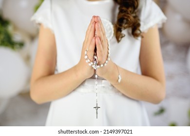 
Hands of the First Communion girl folded in prayer. First Holy Communion. A girl in a white communion dress after receiving her First Holy Communion 