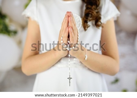 
Hands of the First Communion girl folded in prayer. First Holy Communion. A girl in a white communion dress after receiving her First Holy Communion 
