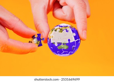 Hands fitting a puzzle piece into an Earth globe set against a vibrant orange background, symbolizing global connection and problem-solving. - Powered by Shutterstock