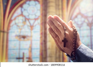 Hands folded in prayer in church with rosary beads and religious cross concept for faith, spirtuality and religion