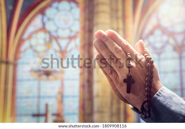Hands folded\
in prayer in church with rosary beads and religious cross concept\
for faith, spirtuality and\
religion