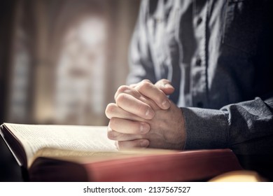 Hands folded in prayer on a Holy Bible in church concept for faith, spirtuality and religion - Shutterstock ID 2137567527