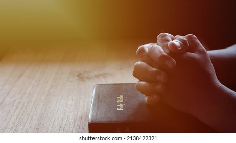 Hands folded in prayer on a Holy Bible in church concept for faith, spirituality and religion, woman praying on holy bible in the morning - Shutterstock ID 2138422321