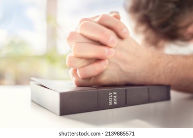 Hands folded in prayer on a Holy Bible in church concept for faith, spirtuality and religion - Shutterstock ID 2139885571