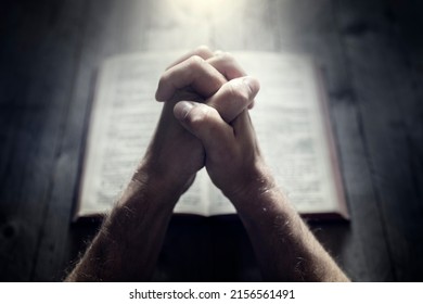 Hands folded in prayer on a Holy Bible in church concept for faith, spirtuality and religion - Shutterstock ID 2156561491