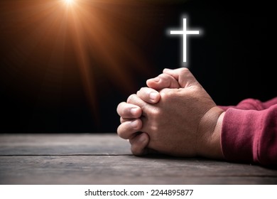 Hands folded in prayer on Holy Bible with cross in church concept for faith, spirituality and religion, Man praying on holy bible withcrucifix in morning. Man hand with Bible and rood praying to god.